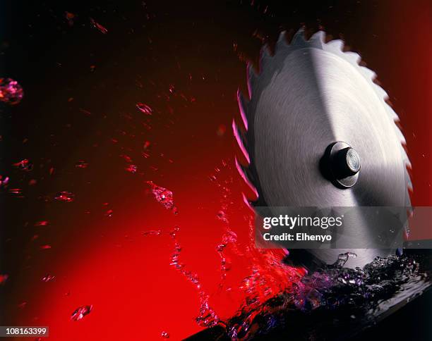 power saw blade in splashing water against red background - saw blade stock pictures, royalty-free photos & images