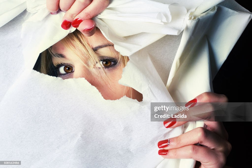 Young Woman Peeking Through Ripped Hole in Paper