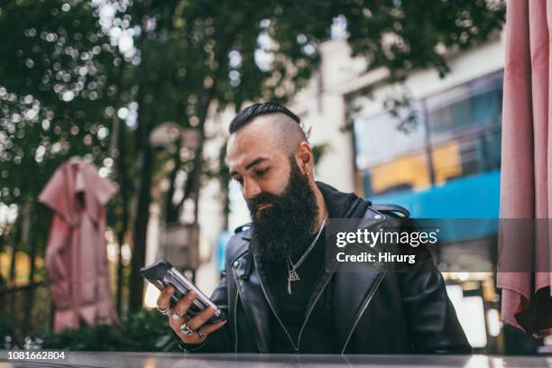 handsome bearded man using phone - cool man leather stock pictures, royalty-free photos & images