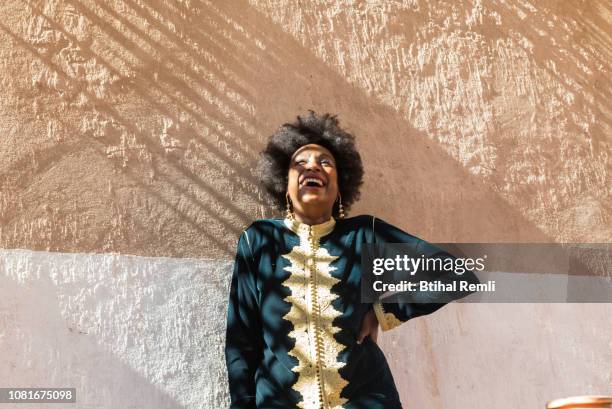 woman standing on a wall with light and shade - moroccan woman stock pictures, royalty-free photos & images
