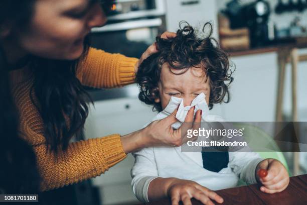 mother helping son to blow his nose - woman home with sick children imagens e fotografias de stock