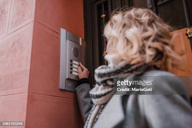mujer tocando una campana de apartamento - door bell fotografías e imágenes de stock