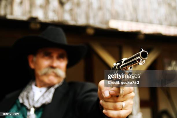 portrait of cowboy holding gun - firing handgun stock pictures, royalty-free photos & images