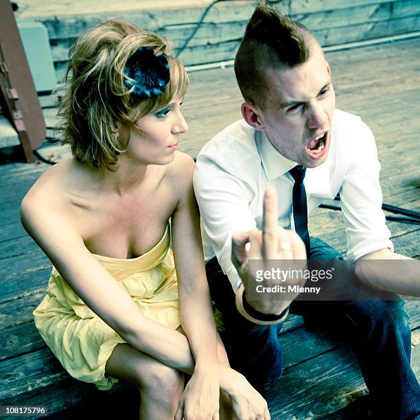 woman sitting beside young man giving middle finger - doigt dhonneur stockfoto's en -beelden