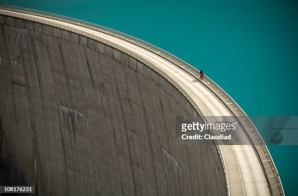 two people looking over the edge of a large dam - people on footpath stock pictures, royalty-free photos & images