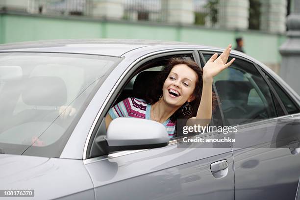 happy young woman driving car - woman waving stock pictures, royalty-free photos & images