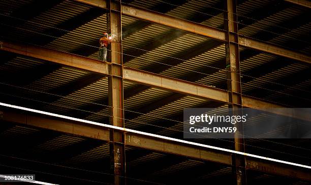 construction worker welding beam on high rise building - smid stockfoto's en -beelden