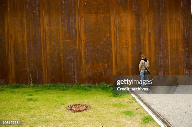 mann urinieren draußen auf rostige wall in der nähe von grünen gras - people peeing stock-fotos und bilder