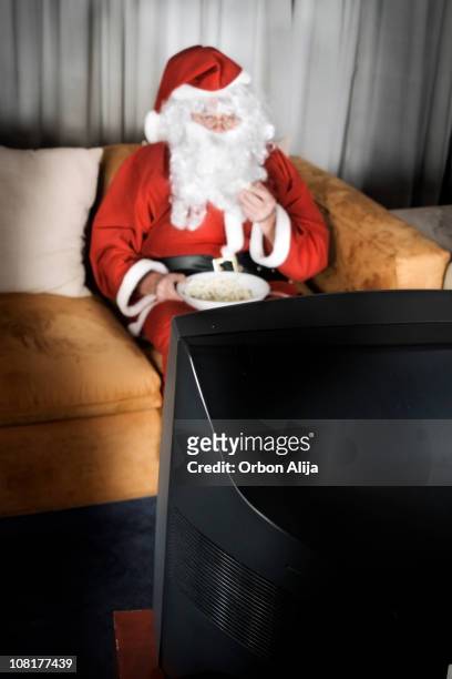 santa clause eating popcorn and watching television - christmas movie stock pictures, royalty-free photos & images