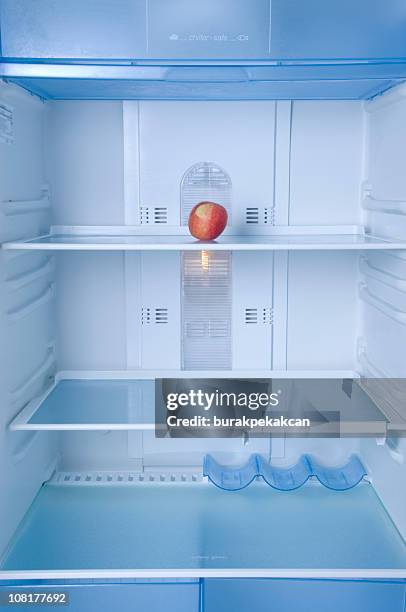lone apple assis dans le vide d'un réfrigérateur - réfrigérateur vide photos et images de collection