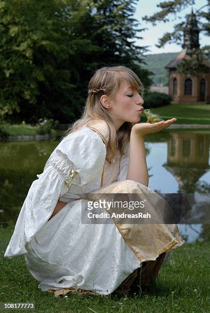 mujer joven princess besando a la rana cerca de estanque - prince andreas fotografías e imágenes de stock