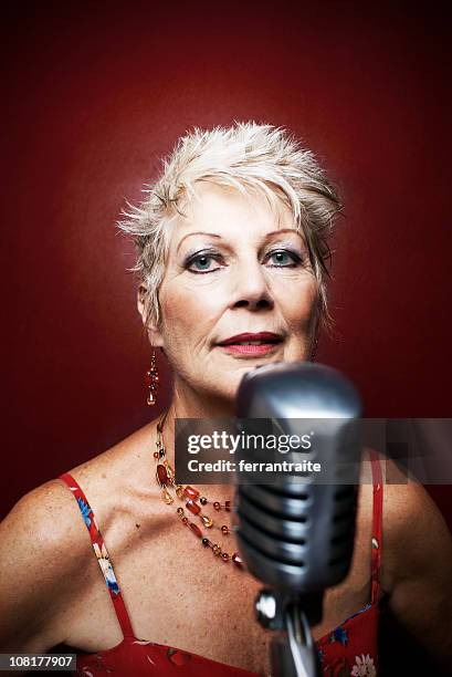 jazz singer posing with retro microphone - speakeasy interior stock pictures, royalty-free photos & images