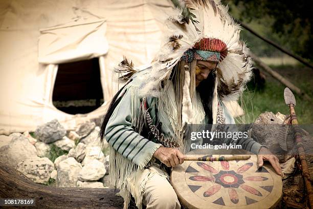 native american chief spielen drum außerhalb indianerzelt - wigwam stock-fotos und bilder