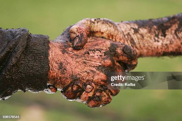 dos hombres cubierto en mud estrechándose las manos - lodo fotografías e imágenes de stock