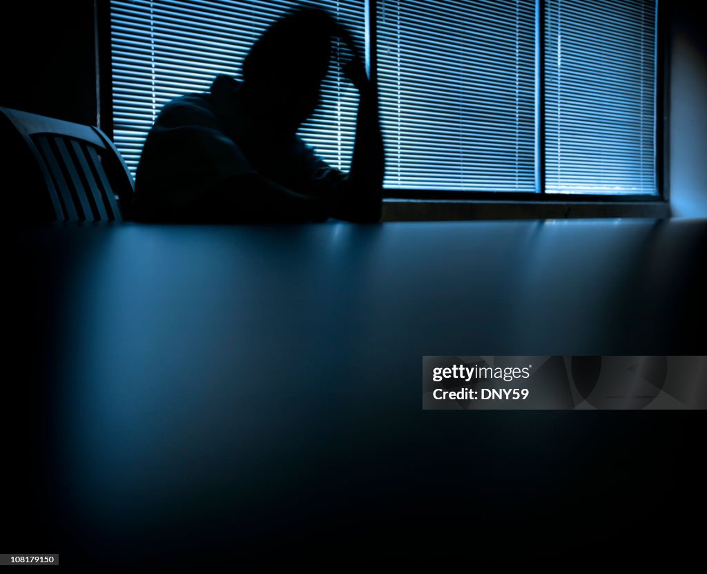 Blurred Shadow of Man Holding Head at Table