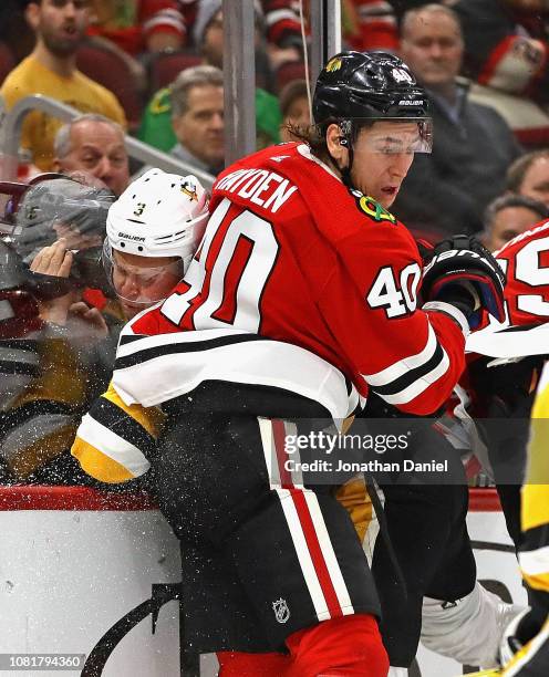 John Hayden of the Chicago Blackhawks checks Olli Maatta of the Pittsburgh Penguins into the boards at the United Center on December 12, 2018 in...