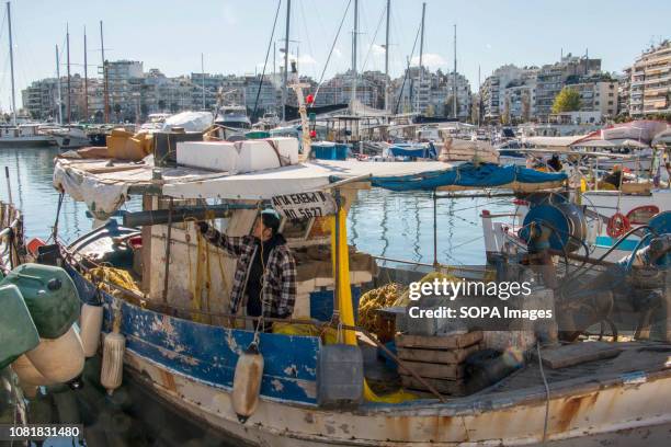 Woman seen having a break on a fishing boat at the Pasalimani port in Piraeus, we meet fishermen in their boats working with their fishing nets.