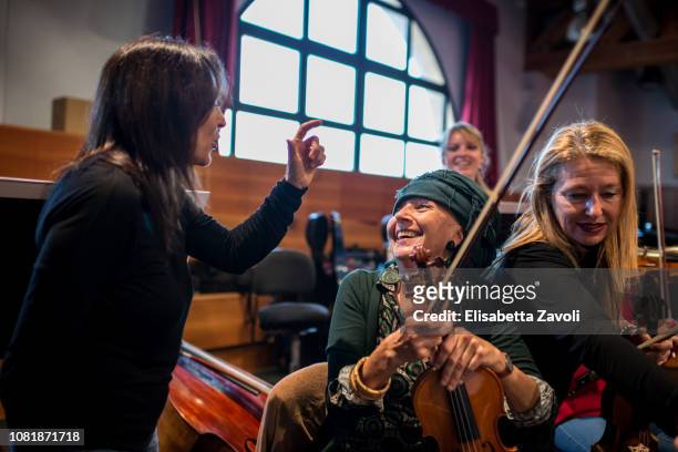 Senior woman with violin at orchestra rehearsal