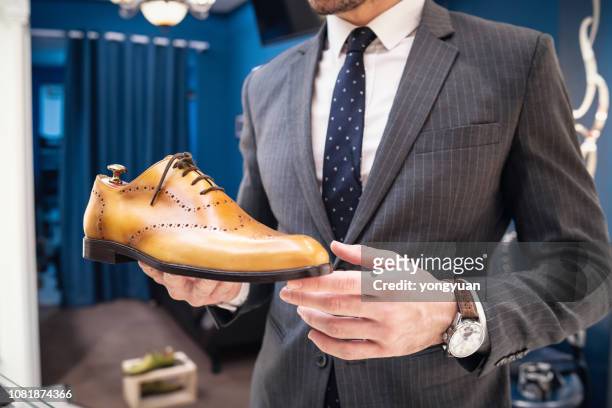 young man holding a leather shoe - dress shoes stock pictures, royalty-free photos & images