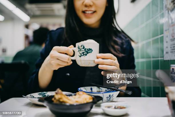 Joyful young woman enjoying Bakuteh and Teh Tarik in a traditional restaurant