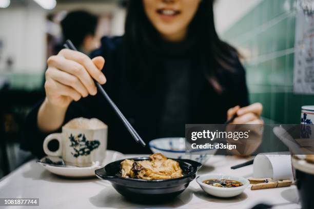 joyful young woman enjoying bakuteh and teh tarik in a traditional restaurant - singapore food stockfoto's en -beelden