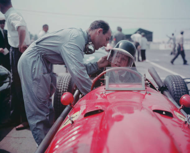British racing driver Stirling Moss adjusts the helmet of Ferrari driver Mike Hawthorn before a race, 1958.