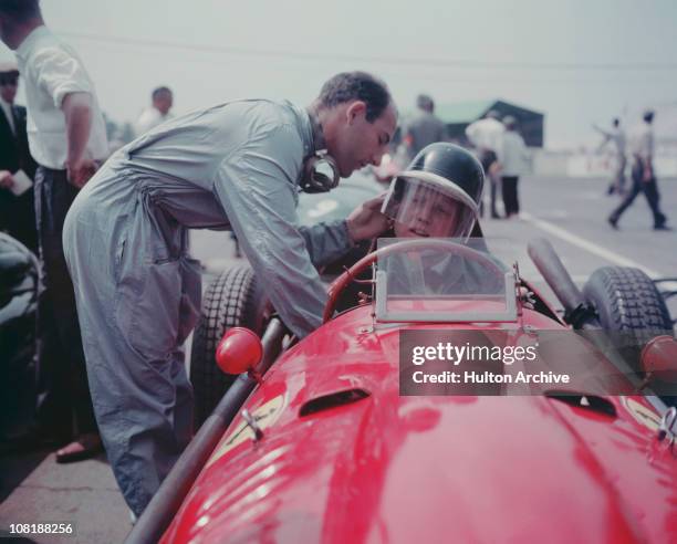 British racing driver Stirling Moss adjusts the helmet of Ferrari driver Mike Hawthorn before a race, 1958.