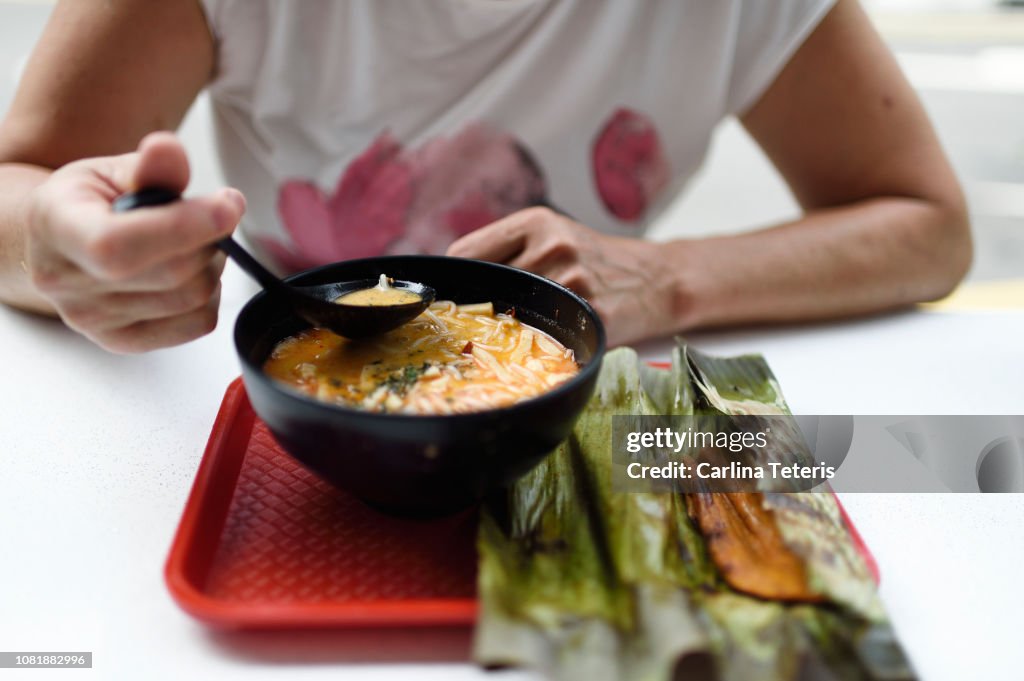 Woman eating Singapore Laksa with otah otah