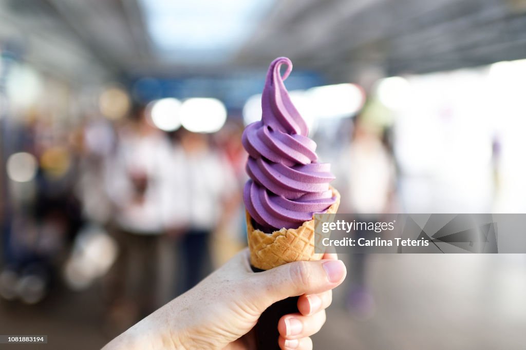 Hand holding a yam soft serve ice cream cone outdoors