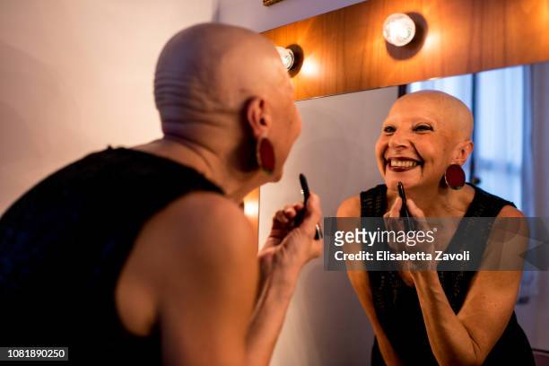 Senior bald woman putting on her makeup