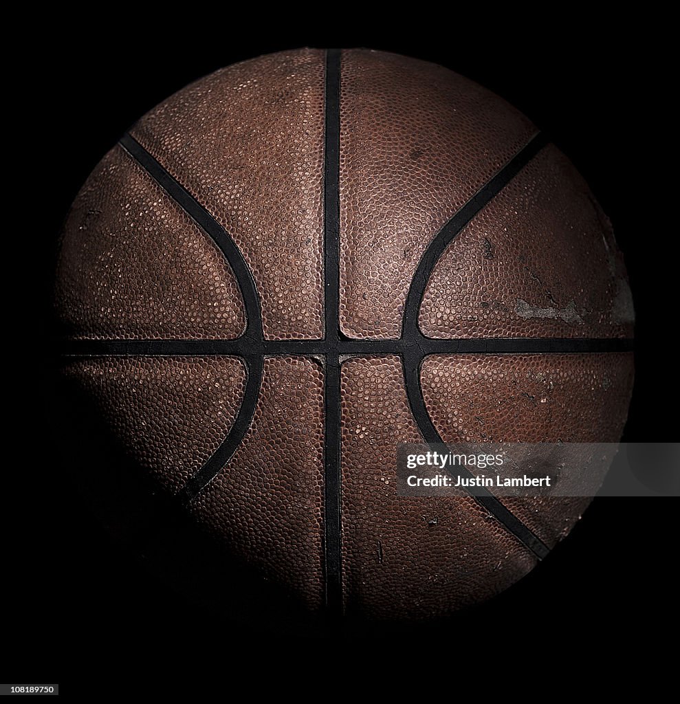 Old used basketball on black