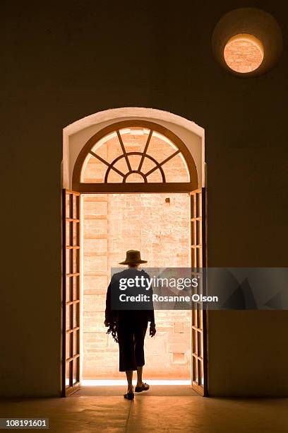 a woman steps through a door into the light. - woman walking out door silhouette stock pictures, royalty-free photos & images