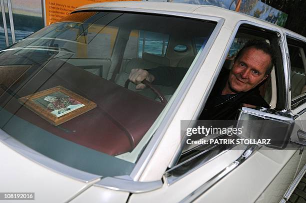 German car dealer Michael Froehlich sits next to a picture of late Pope John Paul II as he poses in a Lincoln Continental car on January 20, 2011 in...