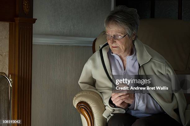 senior woman feeling the cold in her home - cold house stock pictures, royalty-free photos & images