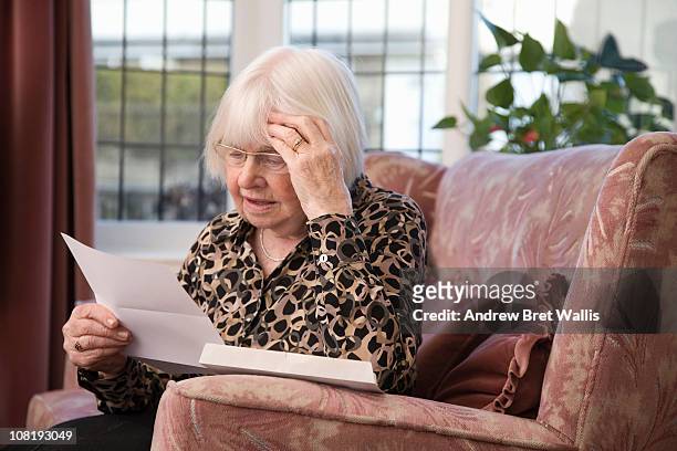 senior woman, head in hands, reading a letter - britain in the 80s stock-fotos und bilder