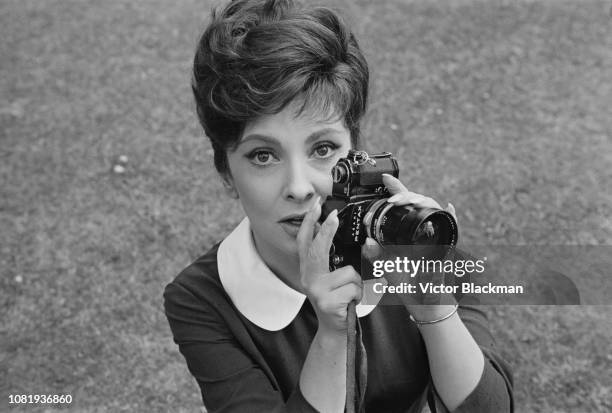 Italian actress, photojournalist and sculptor Gina Lollobrigida holding a Pentax camera, UK, 13th August 1963.