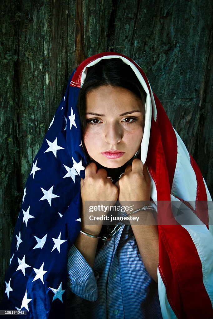 Mujer joven lleva bandera estadounidense y un pie atado al suelo