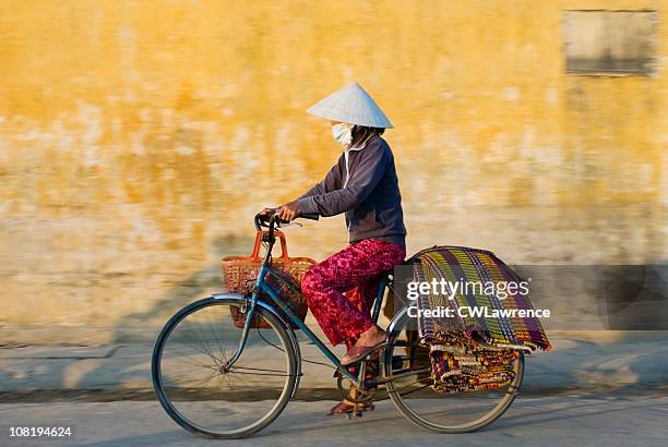 frau tragen traditionelle kleidung in vietnam reiten fahrrad - cycling vietnam stock-fotos und bilder