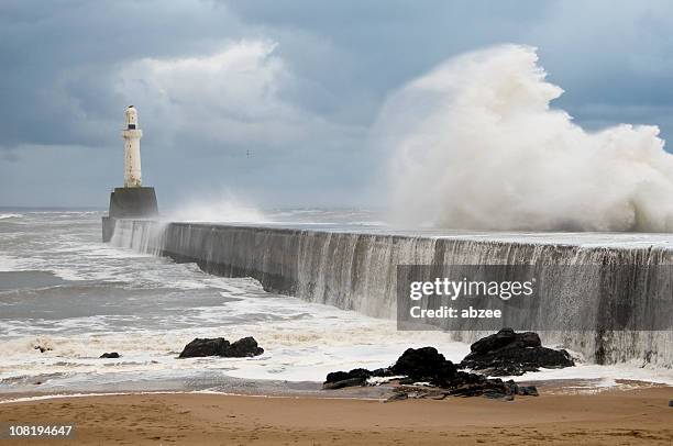 waves crashing on breakwater with lighthouse in aberdeen harbour - aberdeen stock pictures, royalty-free photos & images