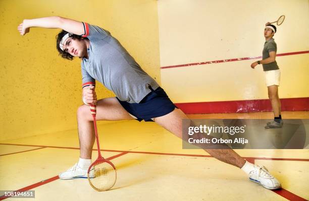 man stretching on squash court holding racket - squash sport stockfoto's en -beelden