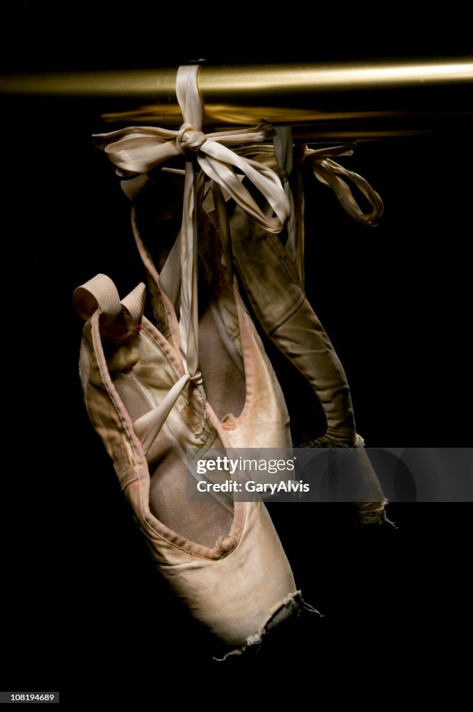 Worn Ballet Shoes Hanging on Brass Rail, Low Key