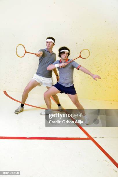 two men posing on court with squash rackets - squash sport stockfoto's en -beelden