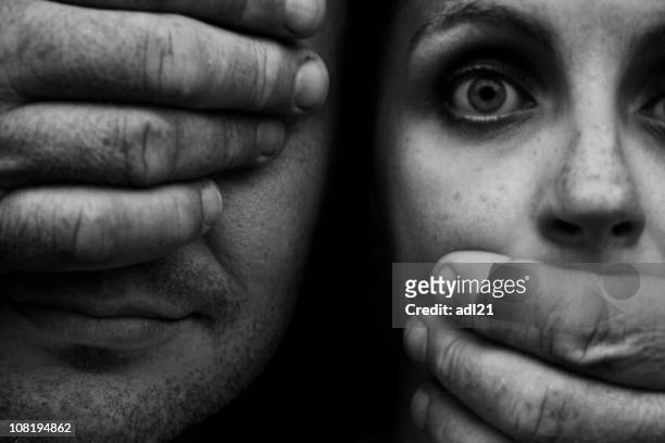 hand vor mann's eye und erschreckter frau mund - domestic violence men stock-fotos und bilder