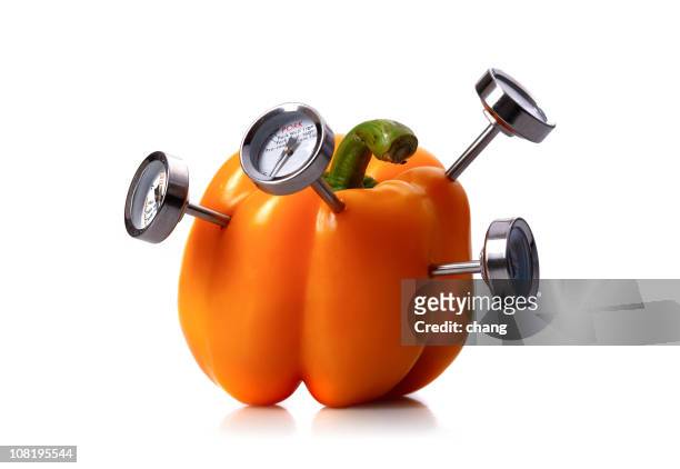 orange bell pepper with meat thermometer's stuck in it - oranje paprika stockfoto's en -beelden