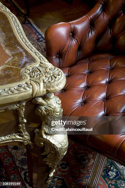 tavolo di antiquariato e chesterfield poltrona in pelle con tappeto orientale - antique sofa styles foto e immagini stock