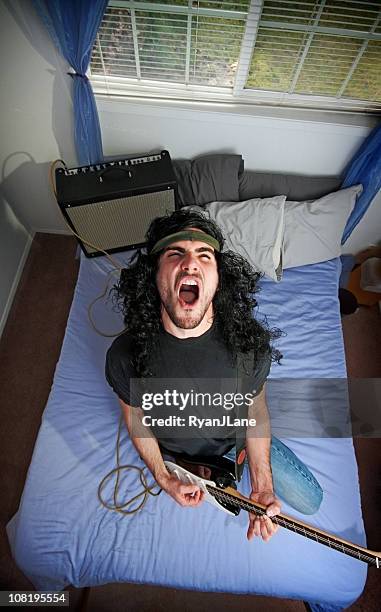 heavy metal rocker in bedroom with electric guitar - metal music stockfoto's en -beelden