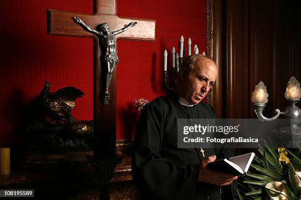 priest reading from bible in church - catholicism stockfoto's en -beelden