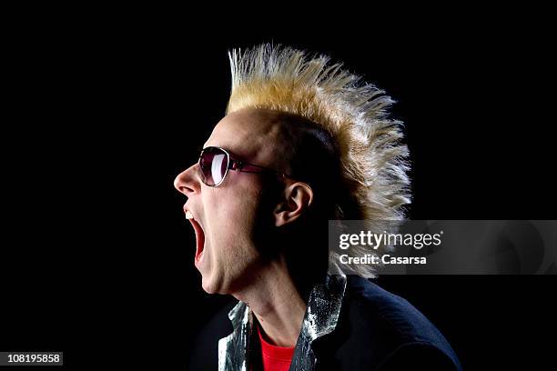 young man with mohawk hairstyle yelling on black background - punk stock pictures, royalty-free photos & images