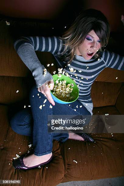 frightened woman spilling popcorn on couch - woman watching horror movie stock pictures, royalty-free photos & images