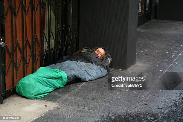 obdachlos im schlafsack auf der straße - homeless person stock-fotos und bilder